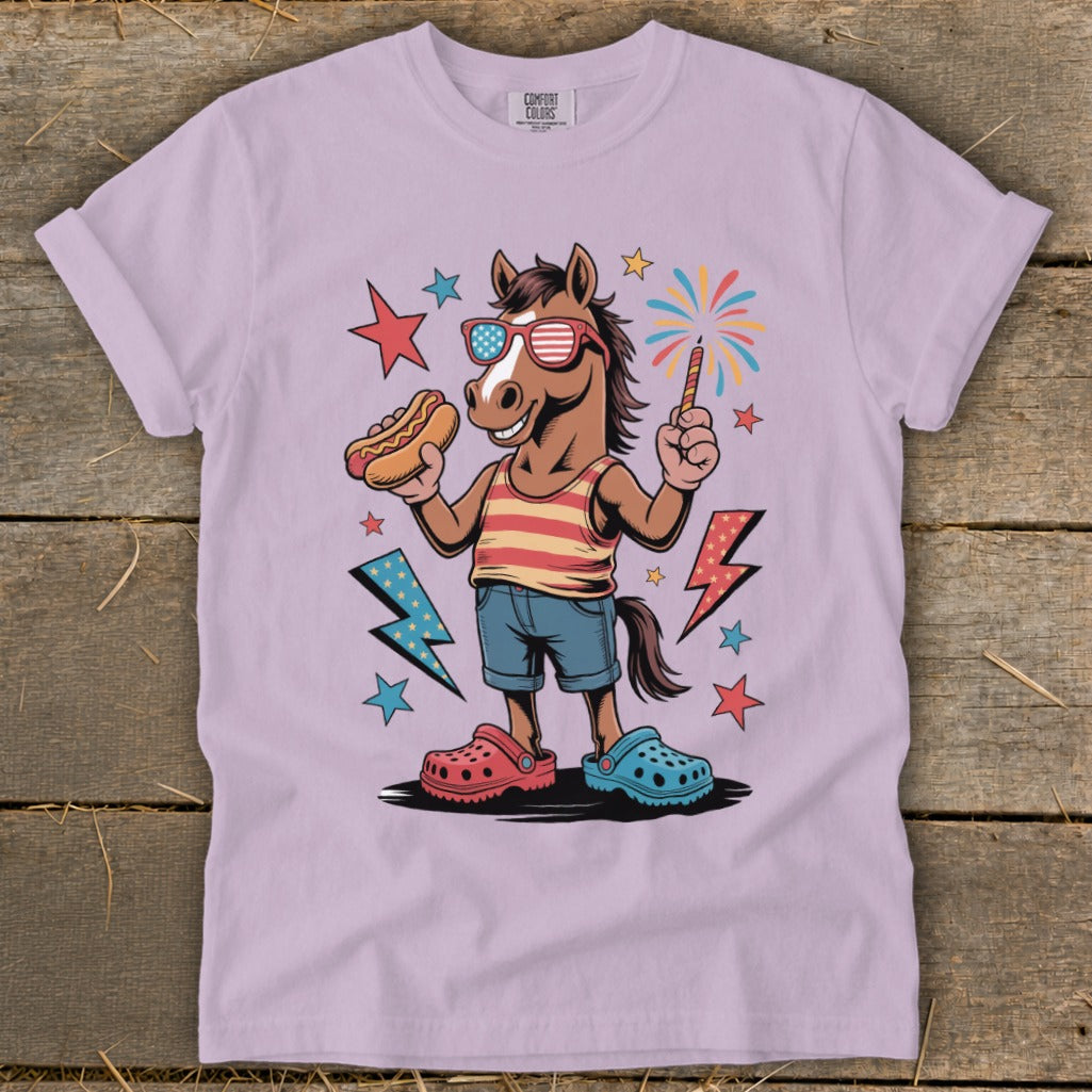 Horse wearing American flag sunglasses holding hot dog and sparkler with fireworks.