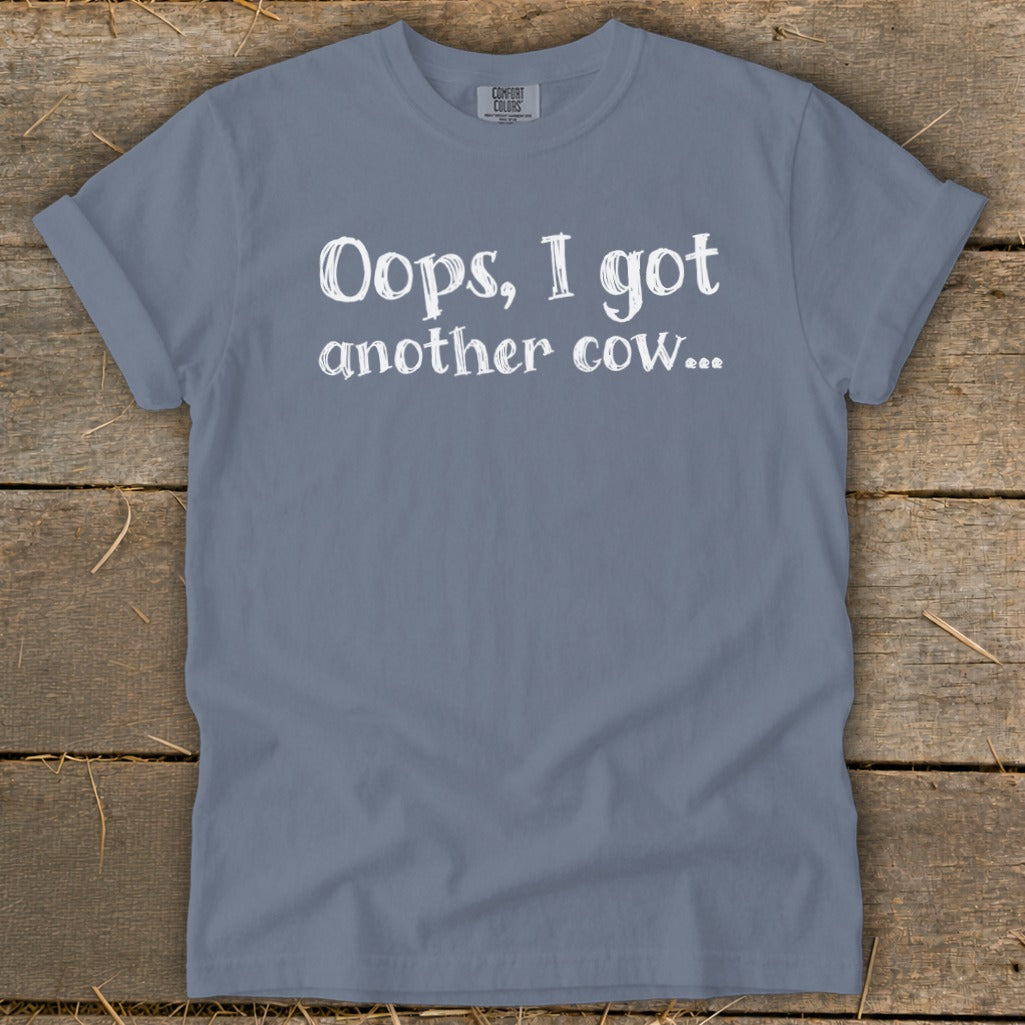 Blue t-shirt with white text reading "Oops, I got another cow...".