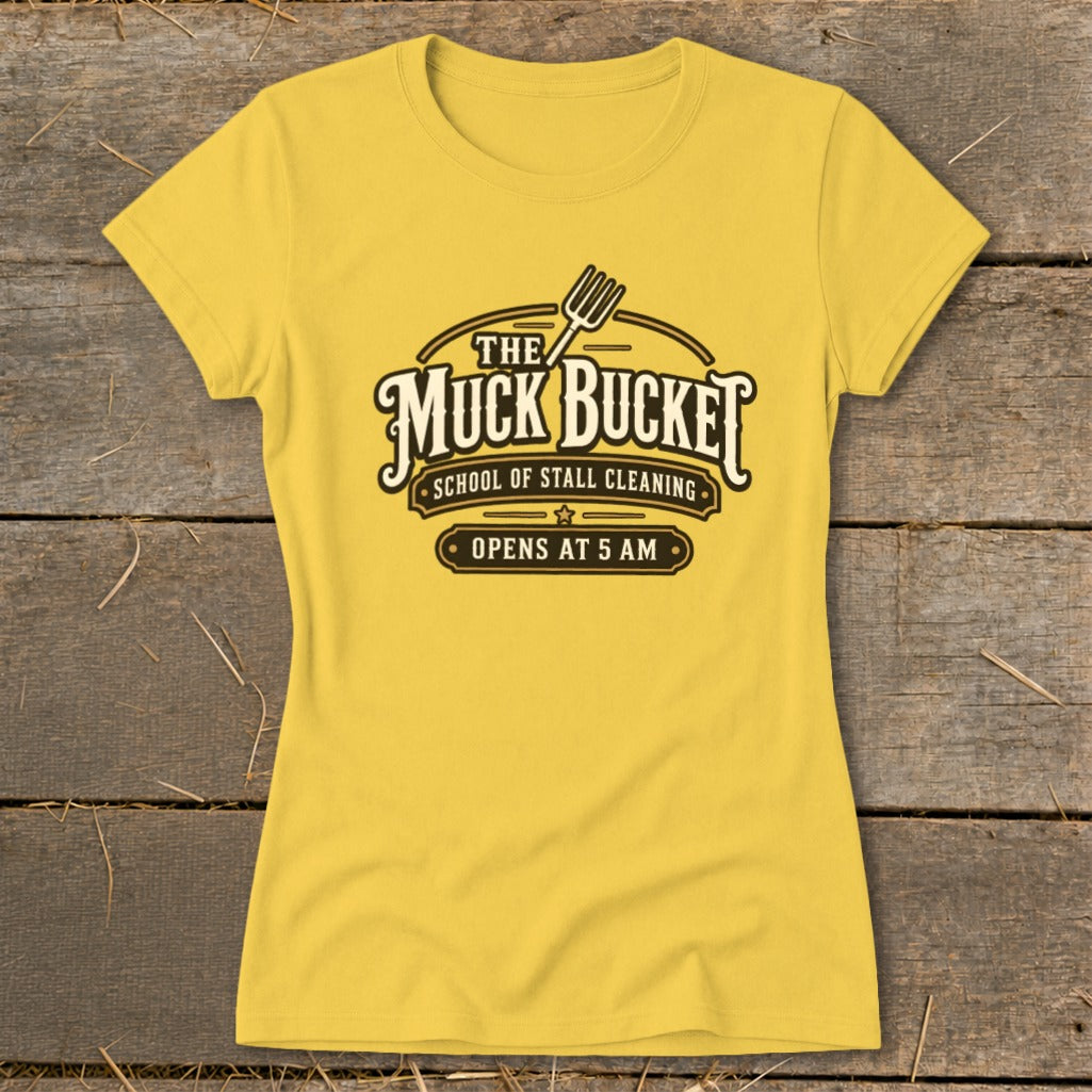 Yellow t-shirt with "The Muck Bucket School of Stall Cleaning Opens at 5 AM" text.