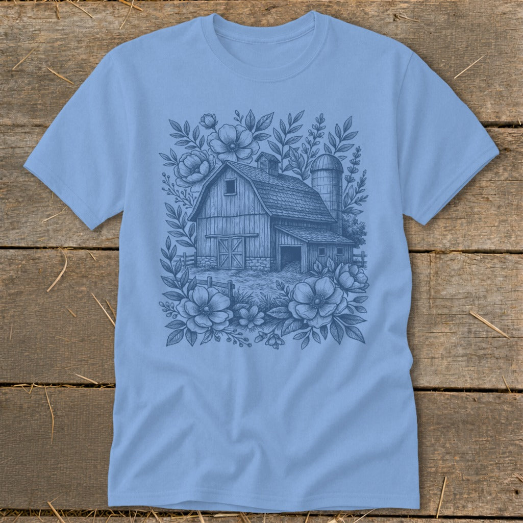 Light blue t-shirt with a sketch of a barn and silo surrounded by flowers.