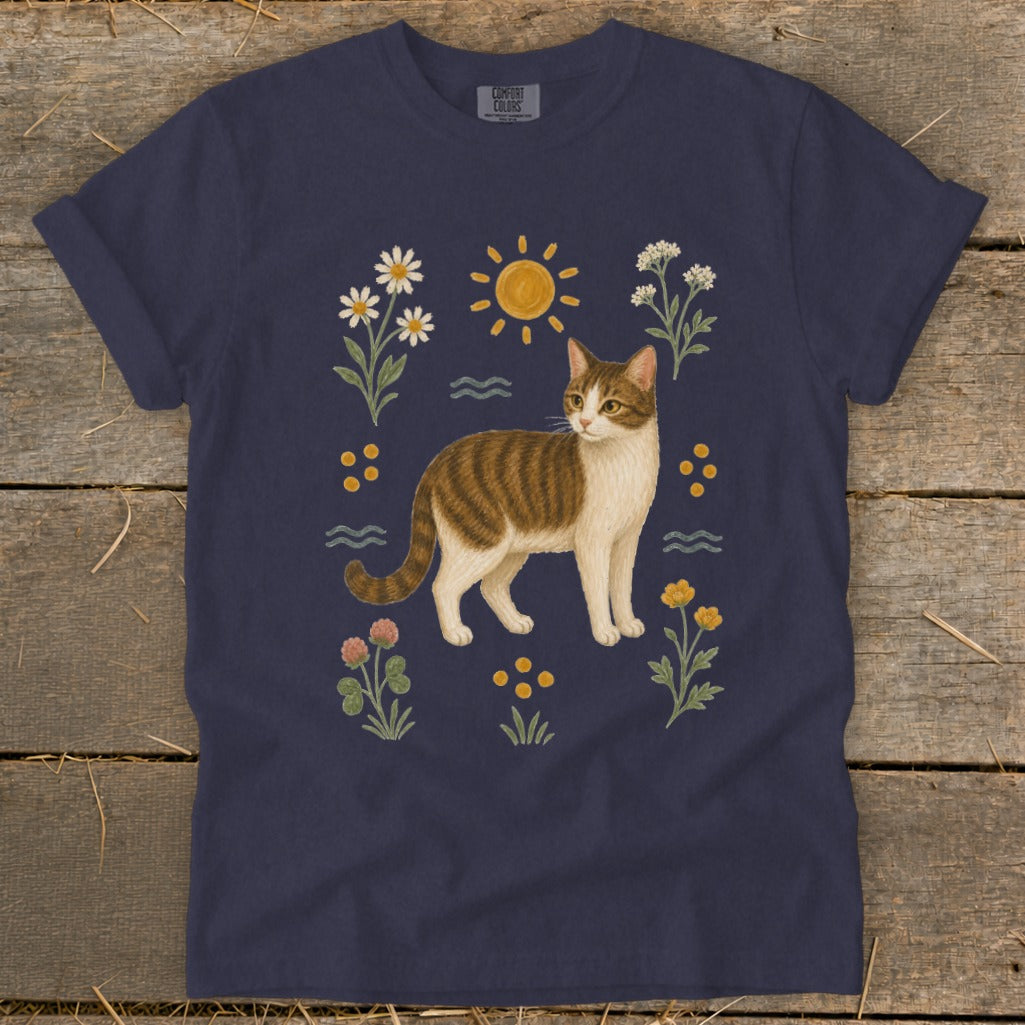 Tabby cat with flowers, sun, and wavy lines design on a navy blue t-shirt.
