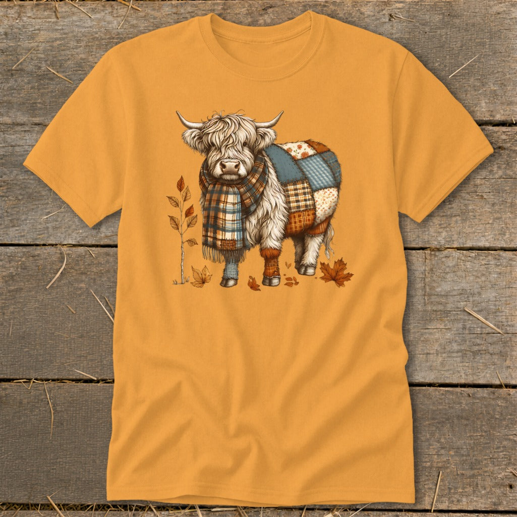 Highland cow wearing a scarf and patchwork blanket, with autumn leaves.
