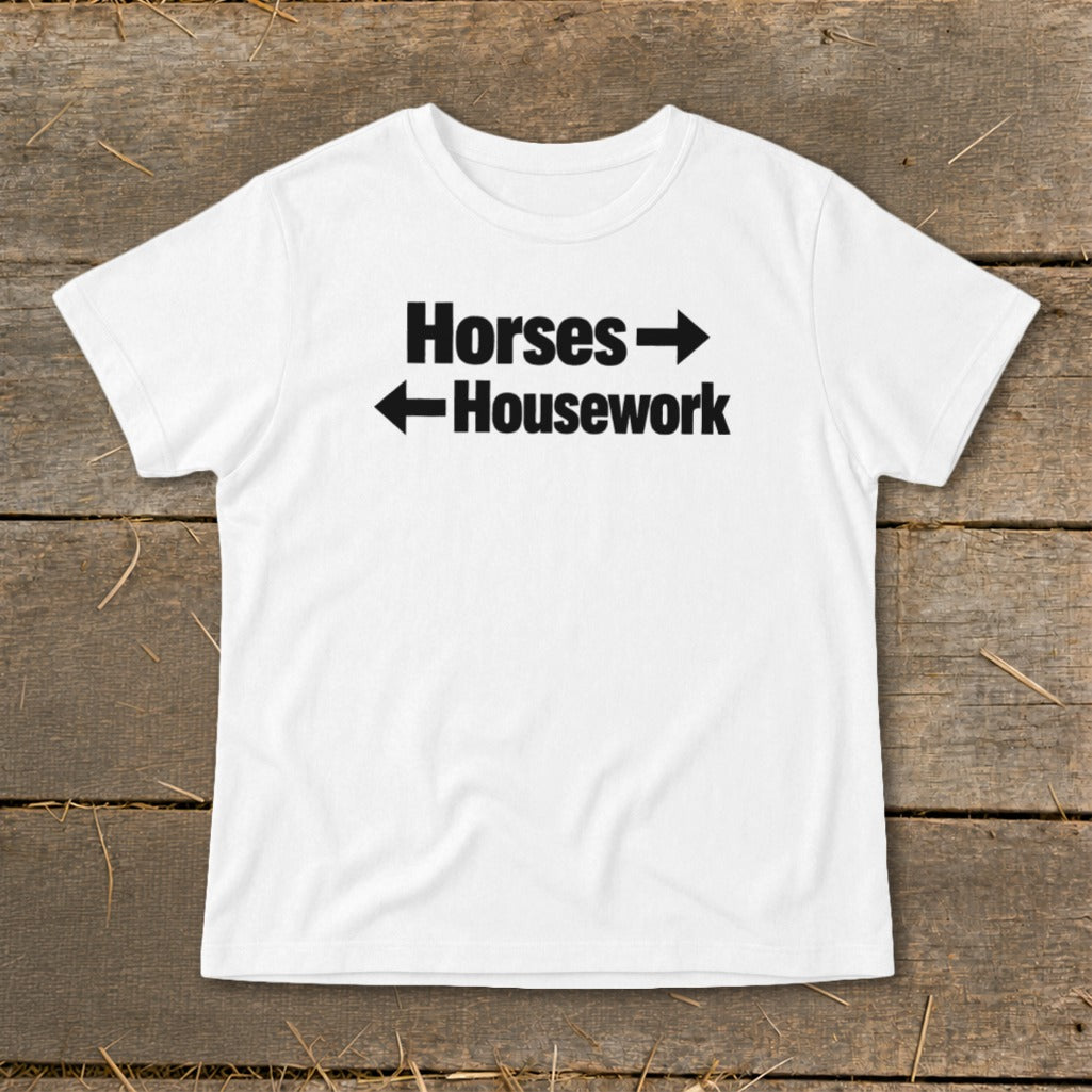 A white t-shirt with black text that reads Horses with a right arrow and Housework with a left arrow.