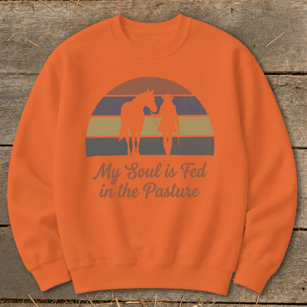 Orange sweatshirt with "My Soul is Fed in the Pasture" text and horse and rider silhouette.