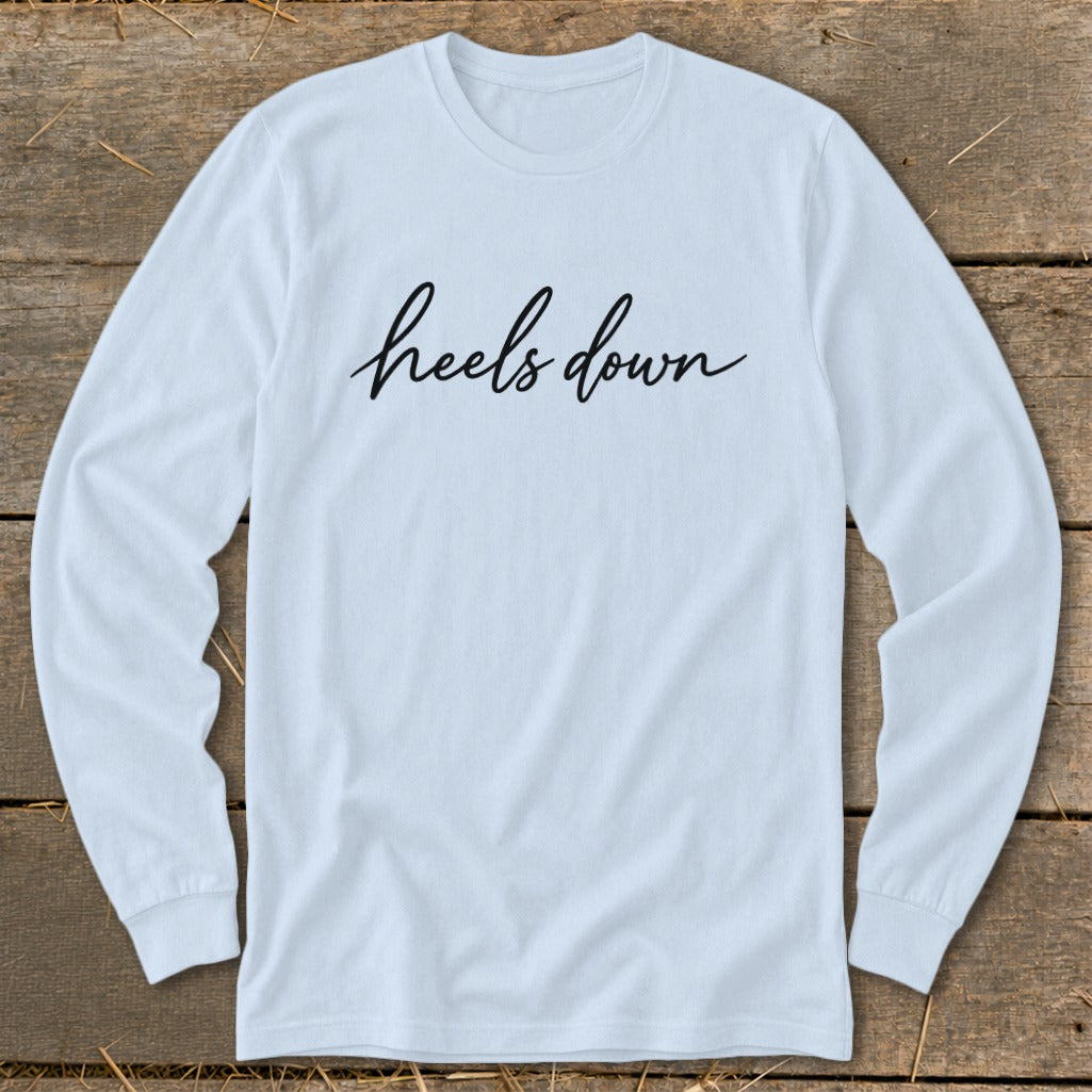 Light blue long-sleeve shirt with black cursive text that reads "heels down".
