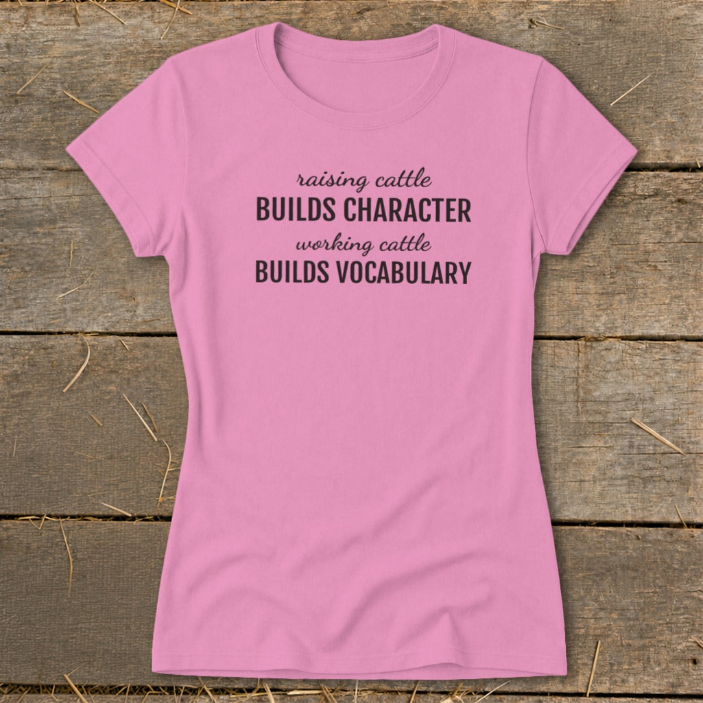Pink t-shirt with text "raising cattle BUILDS CHARACTER working cattle BUILDS VOCABULARY".