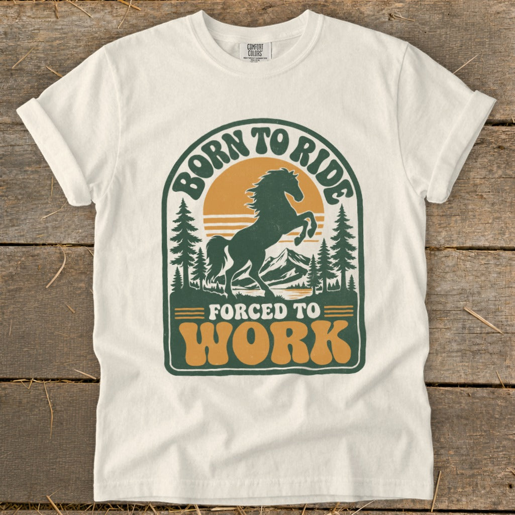 T-shirt with graphic of a rearing horse, mountains, trees, and text "Born to Ride Forced to Work".