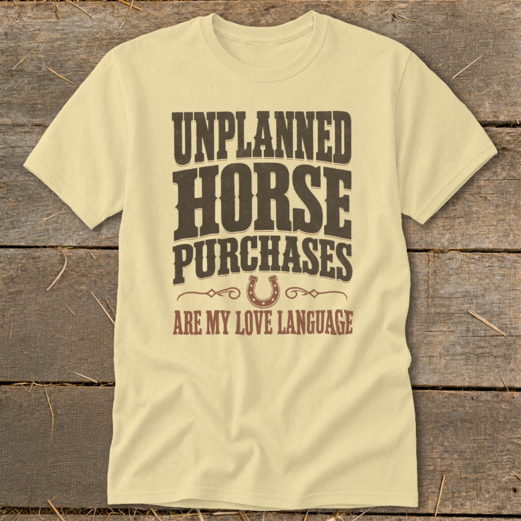 Light yellow t-shirt with brown text reading "Unplanned Horse Purchases Are My Love Language" and a horseshoe graphic.