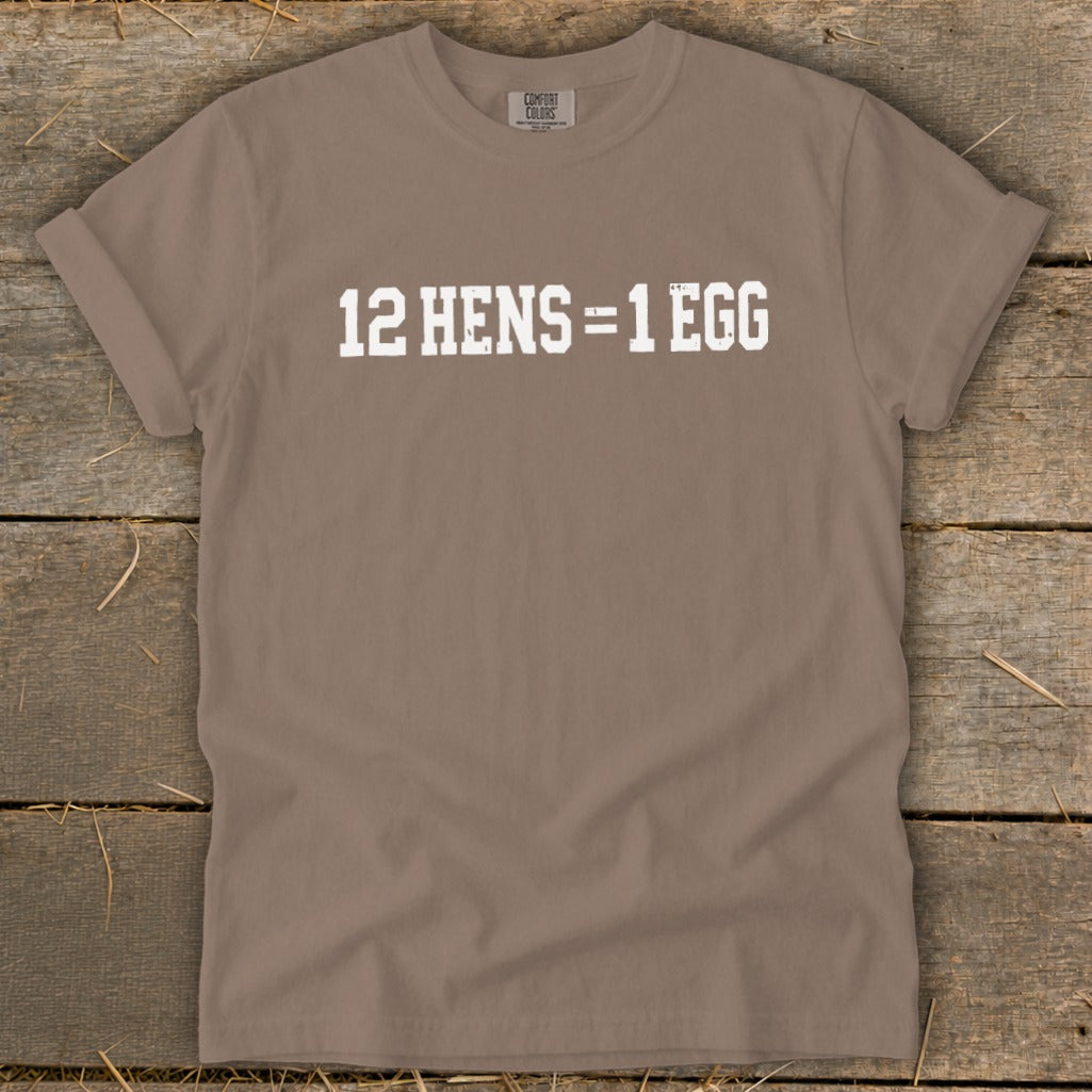A brown short-sleeve t-shirt with the white distressed text "12 HENS = 1 EGG" printed on the front.