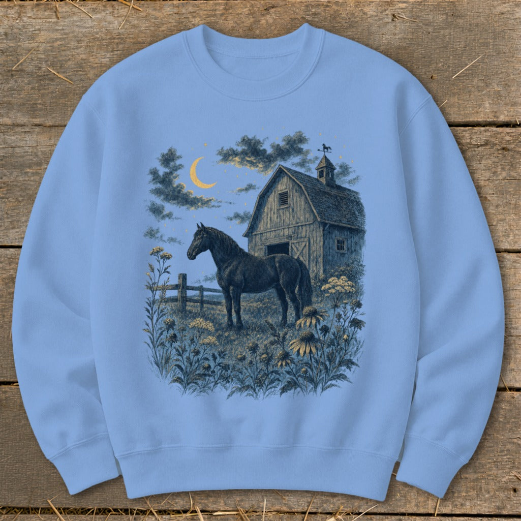 Black horse in field with barn, moon, and stars graphic on light blue sweatshirt.