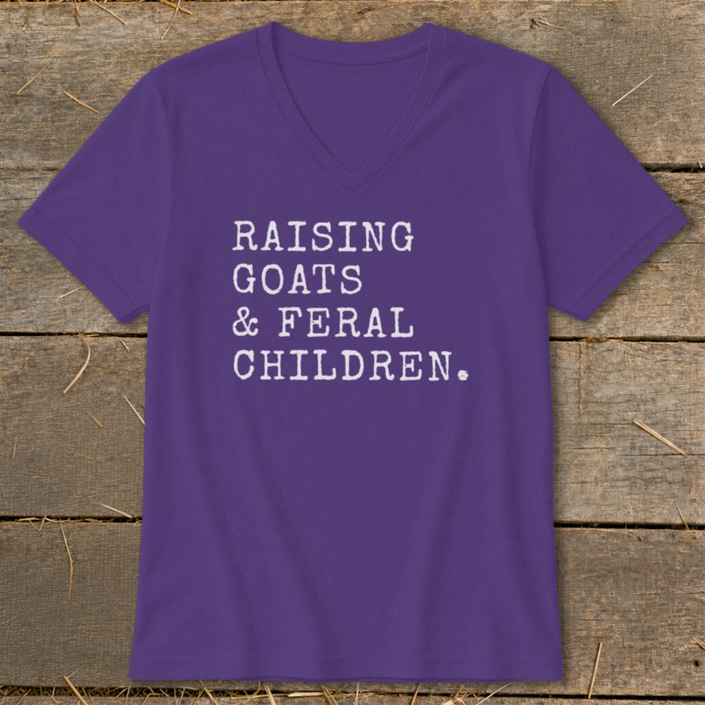 Purple v-neck t-shirt with white text: Raising Goats & Feral Children.