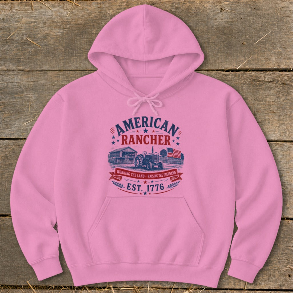 Pink hoodie with "American Rancher" graphic, tractor, barn, and flag.