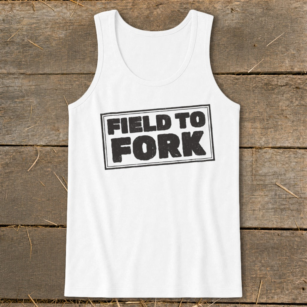 A white tank top with the black text FIELD TO FORK laid flat on a rustic wooden surface.