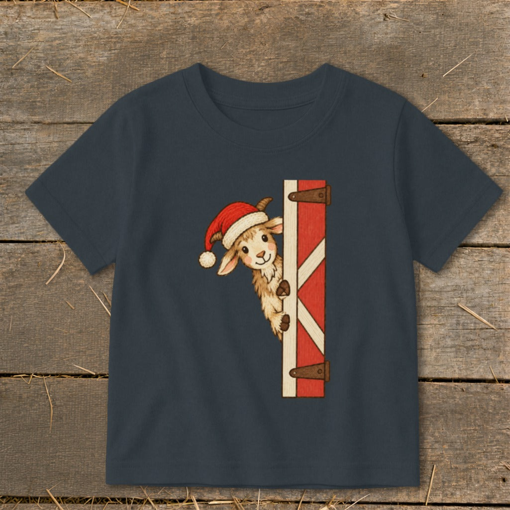T-shirt with a goat wearing a Santa hat peeking from behind a barn door graphic.