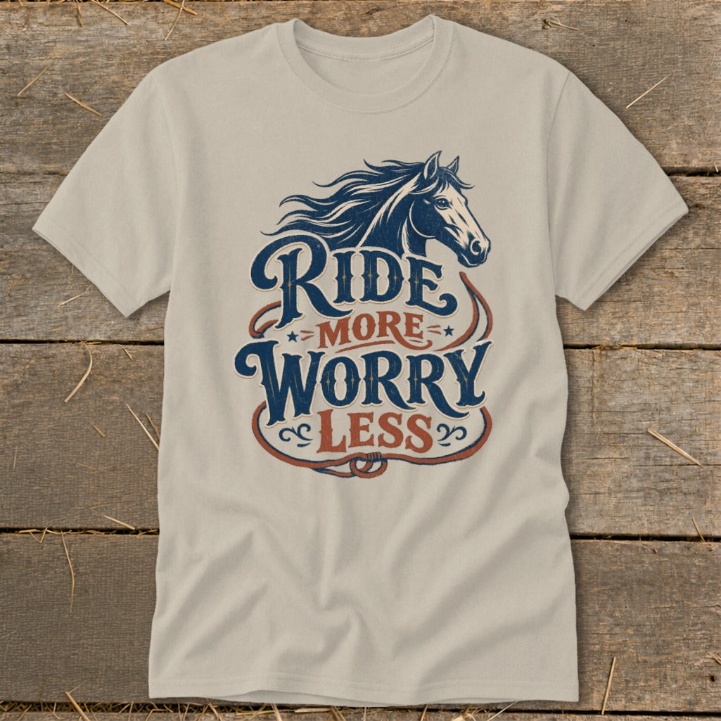 Light beige t-shirt with a dark blue horse graphic and "Ride More Worry Less" text.