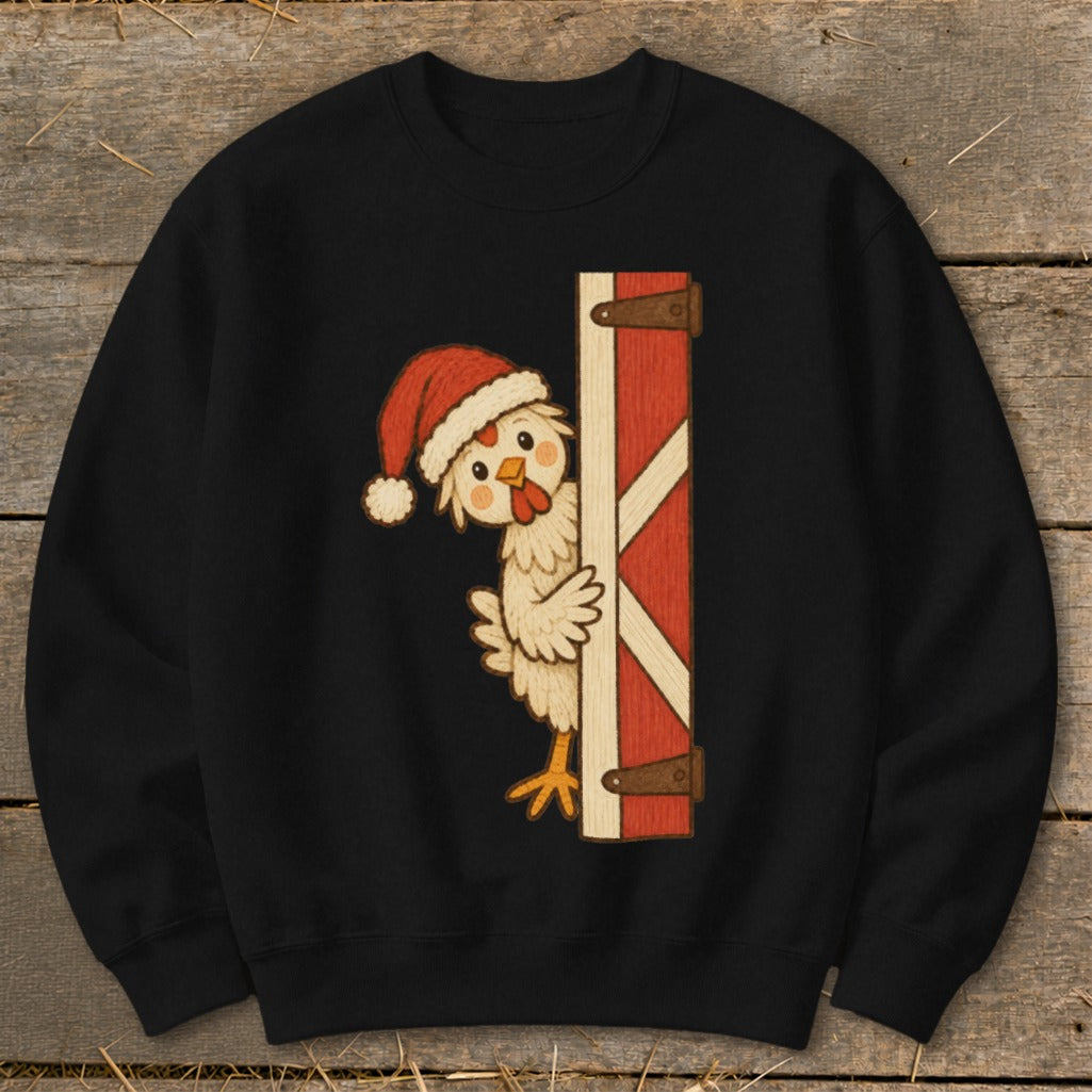 Chicken wearing Santa hat peeking around a barn door on a black sweatshirt.