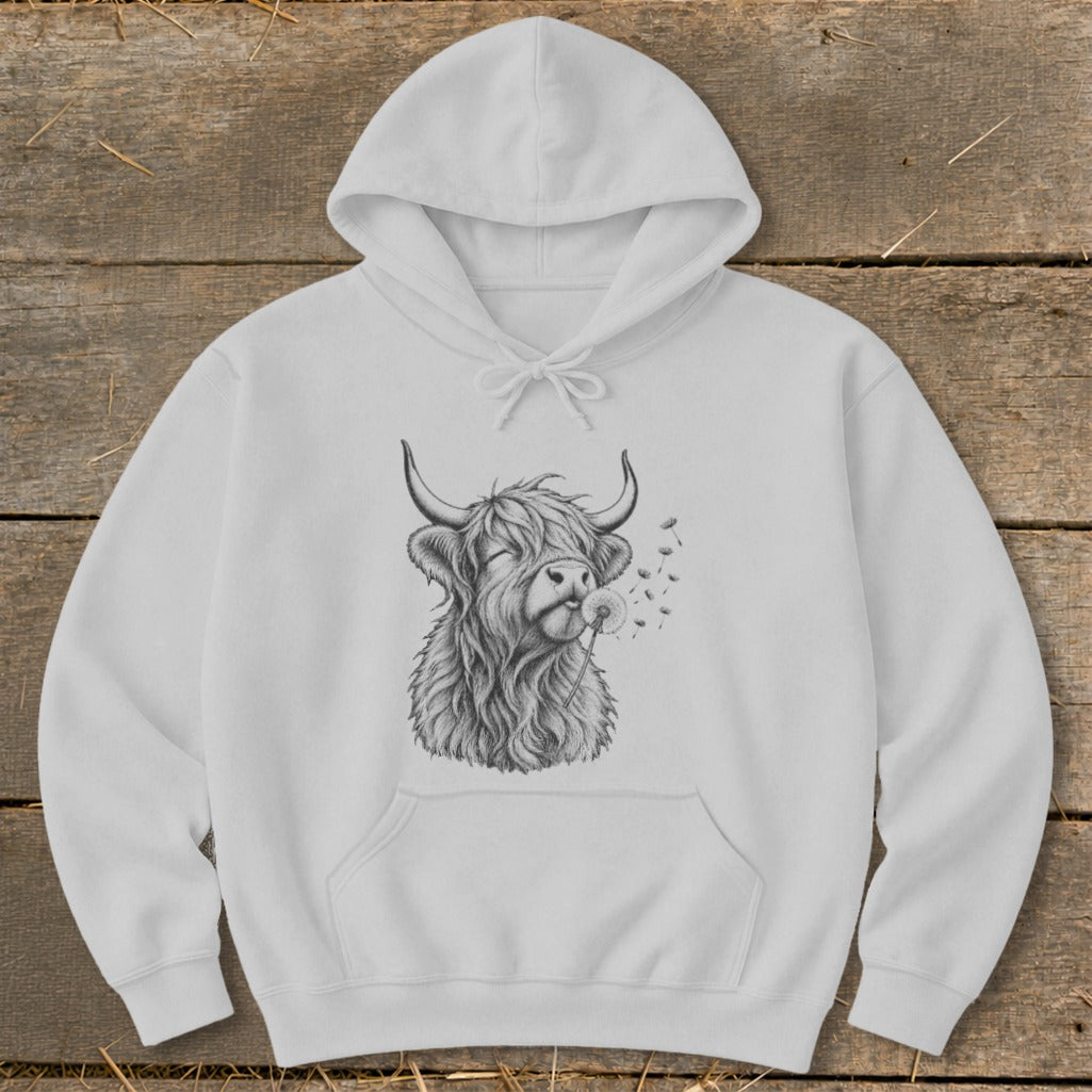 White hoodie with a black and white drawing of a Highland cow blowing dandelion seeds.