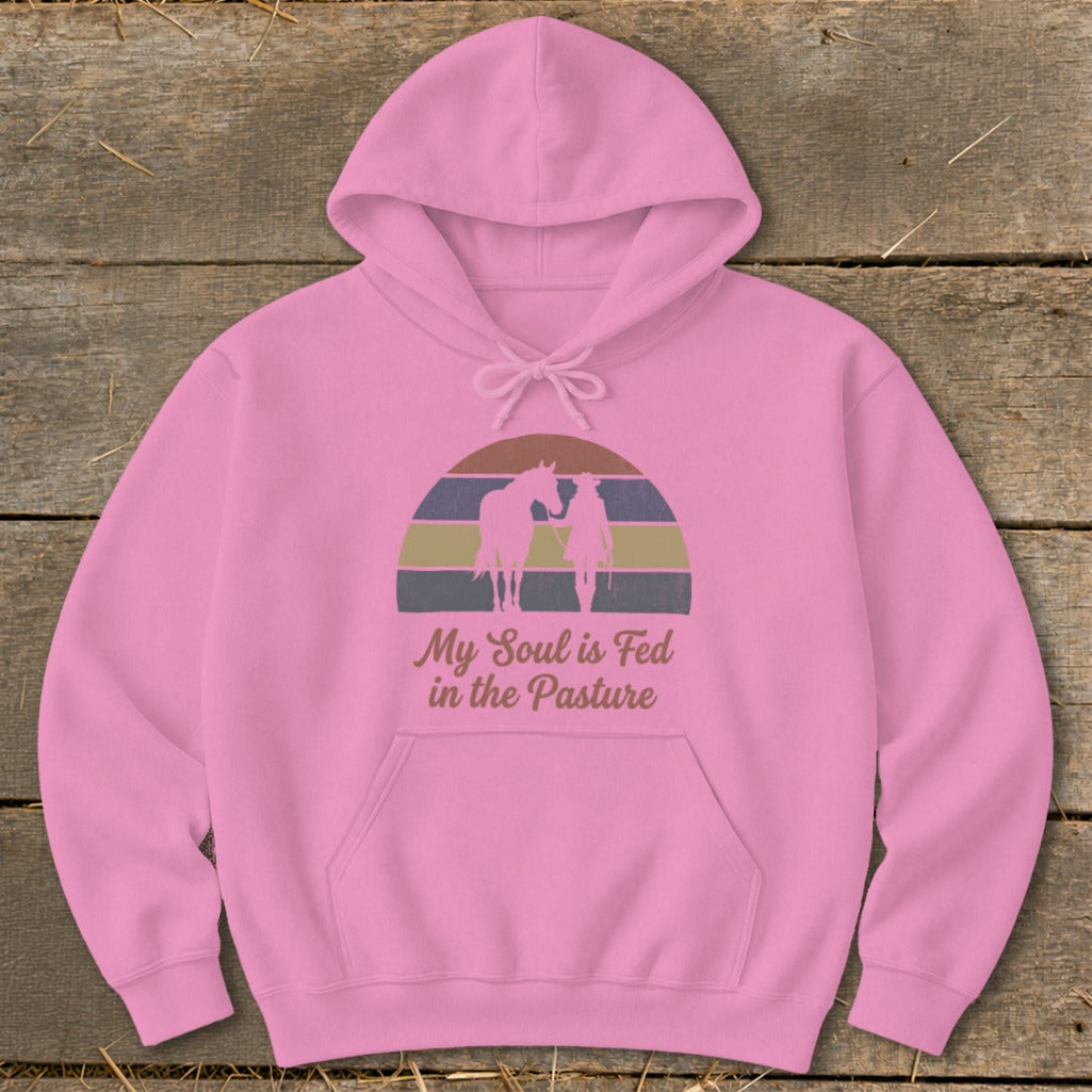 Pink hoodie with horse and rider silhouettes and the text "My Soul is Fed in the Pasture".