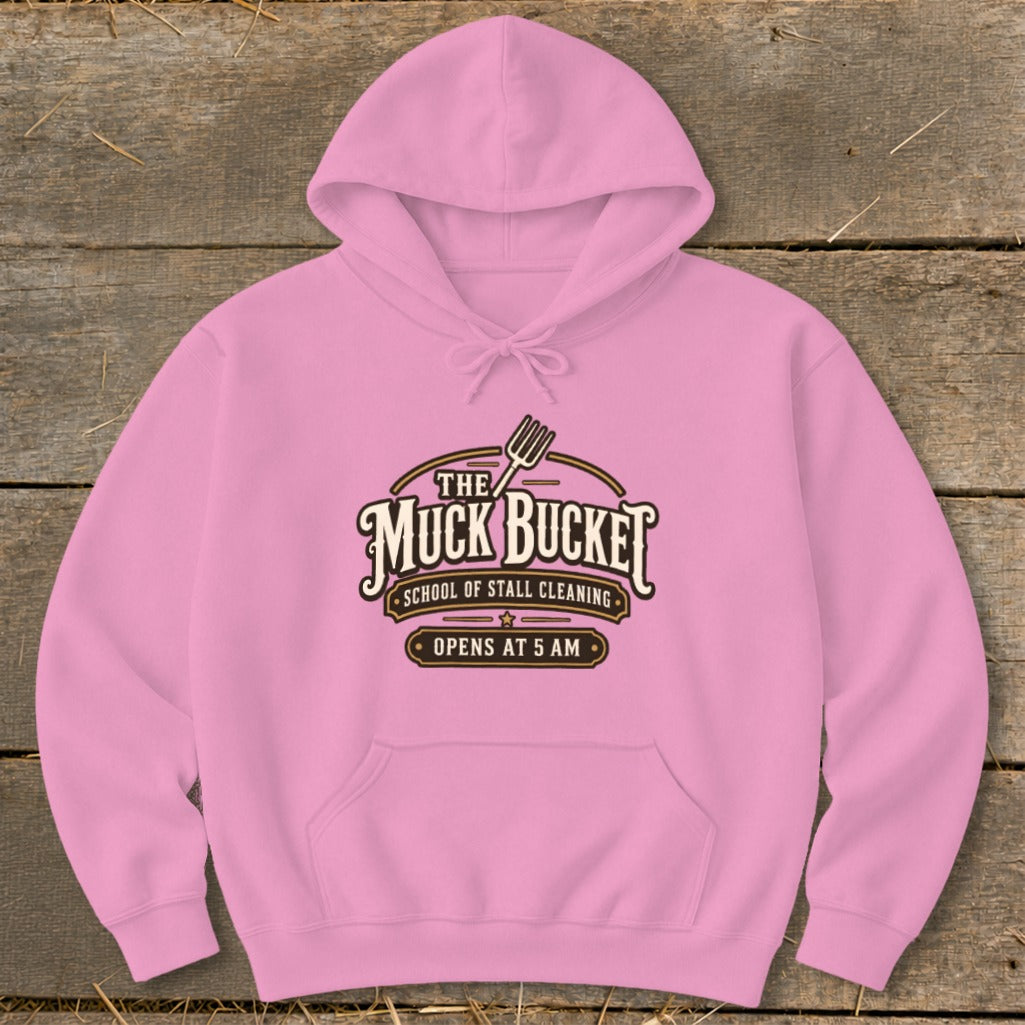 Pink hoodie with "The Muck Bucket School of Stall Cleaning Opens at 5 AM" logo.