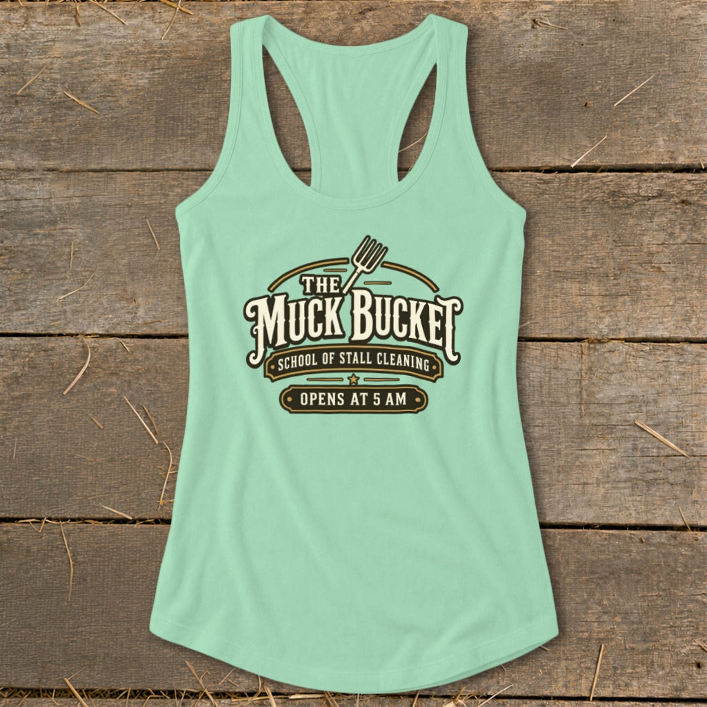 Light green tank top with "The Muck Bucket School of Stall Cleaning Opens at 5 AM" graphic.