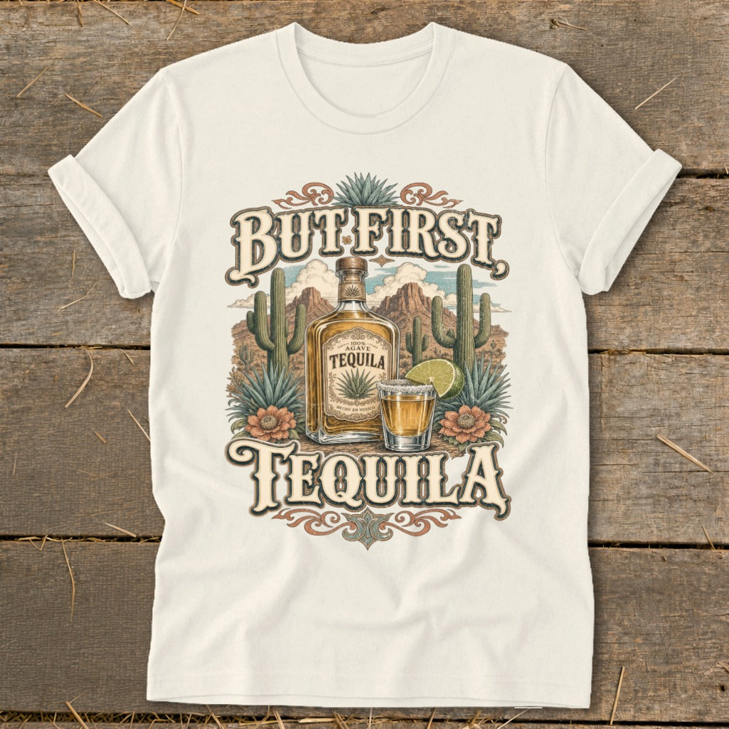 Cream t-shirt with "But First Tequila" graphic featuring a tequila bottle, shot glass, cacti, and desert landscape.