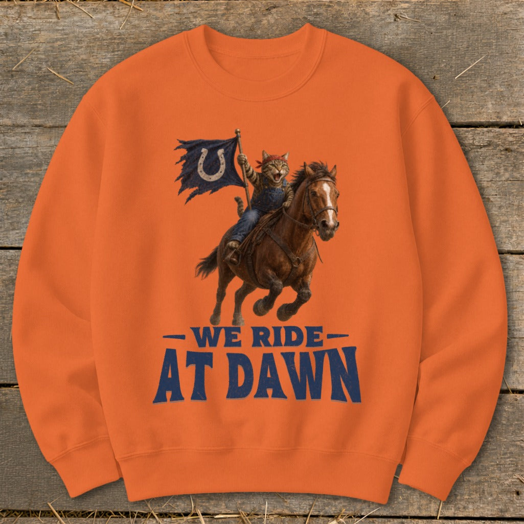Orange sweatshirt with cat on horse, holding a blue flag with a horseshoe. Text reads "WE RIDE AT DAWN."