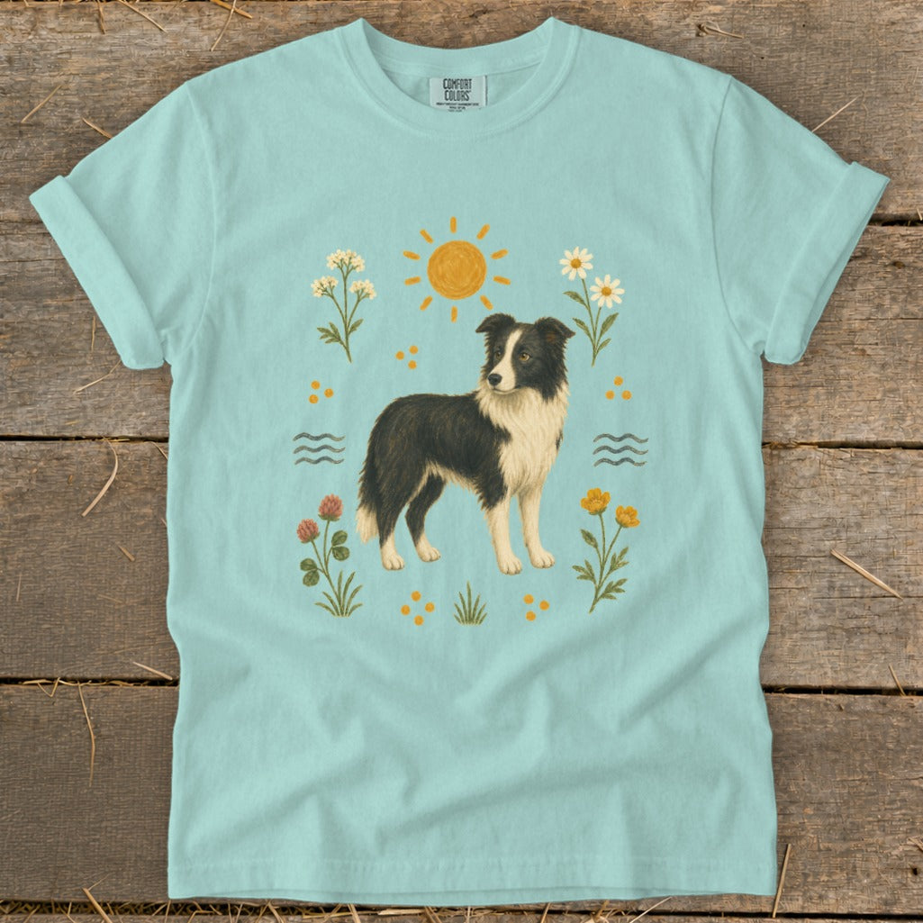 Light blue t-shirt with a border collie dog surrounded by flowers, sun, and water.