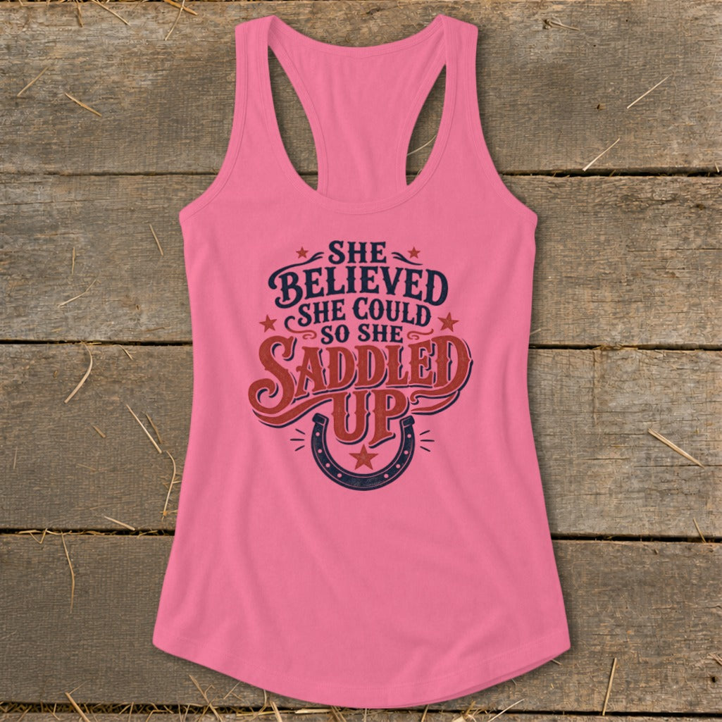 Pink tank top with text "She believed she could so she saddled up" and horseshoe.