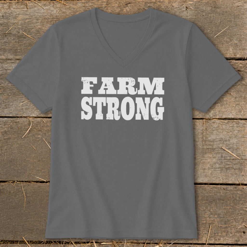 A dark gray V-neck t-shirt with distressed white text reading FARM STRONG on a rustic wooden background.