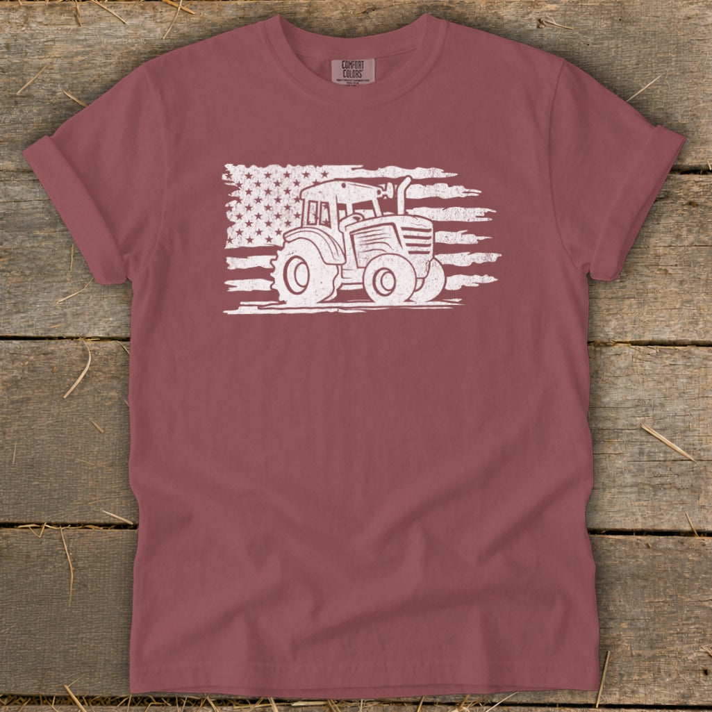 Tractor graphic on distressed American flag design on a maroon t-shirt.