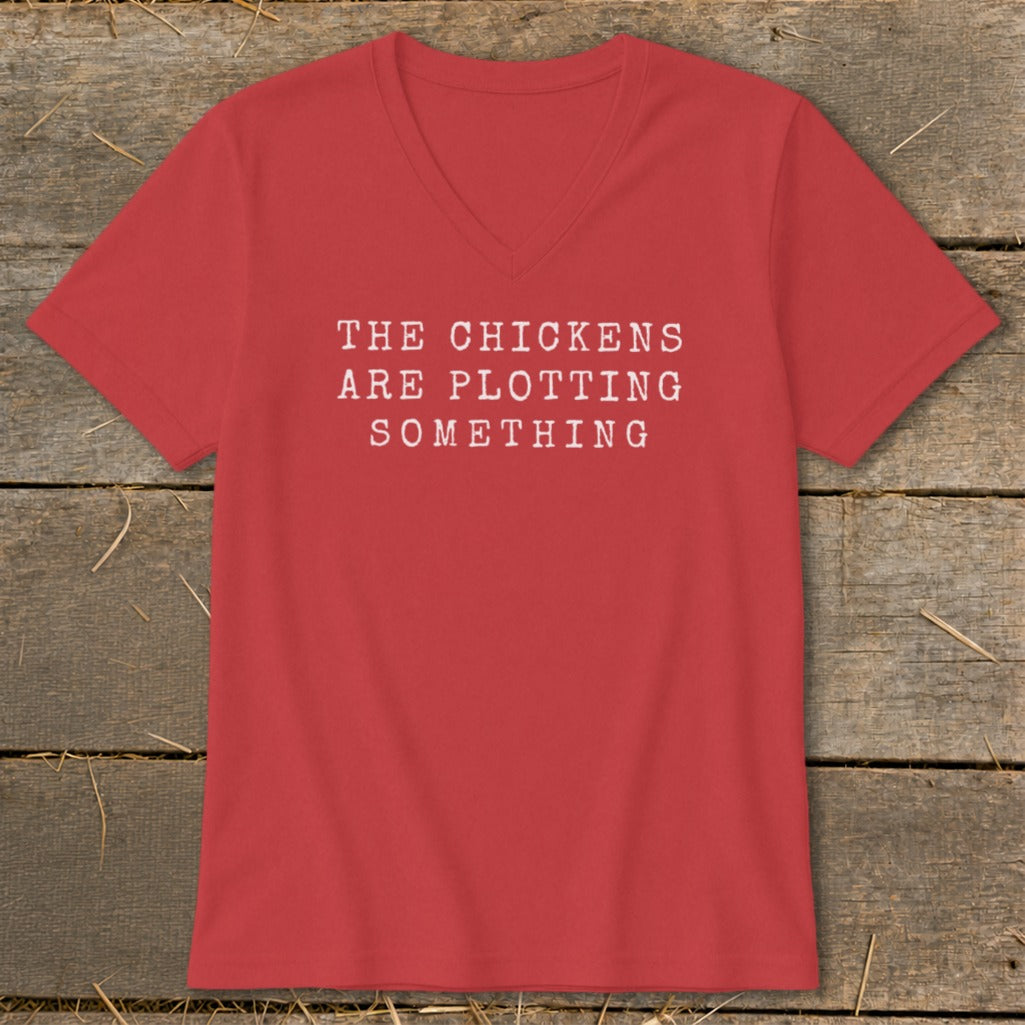 Red V-neck t-shirt with white text reading "THE CHICKENS ARE PLOTTING SOMETHING".