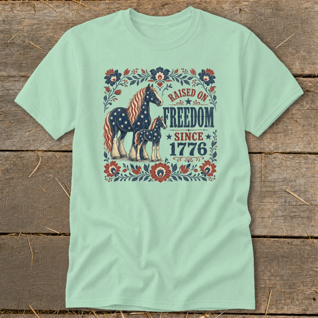 Mint t-shirt with a graphic of two horses and the text "Raised on Freedom Since 1776".