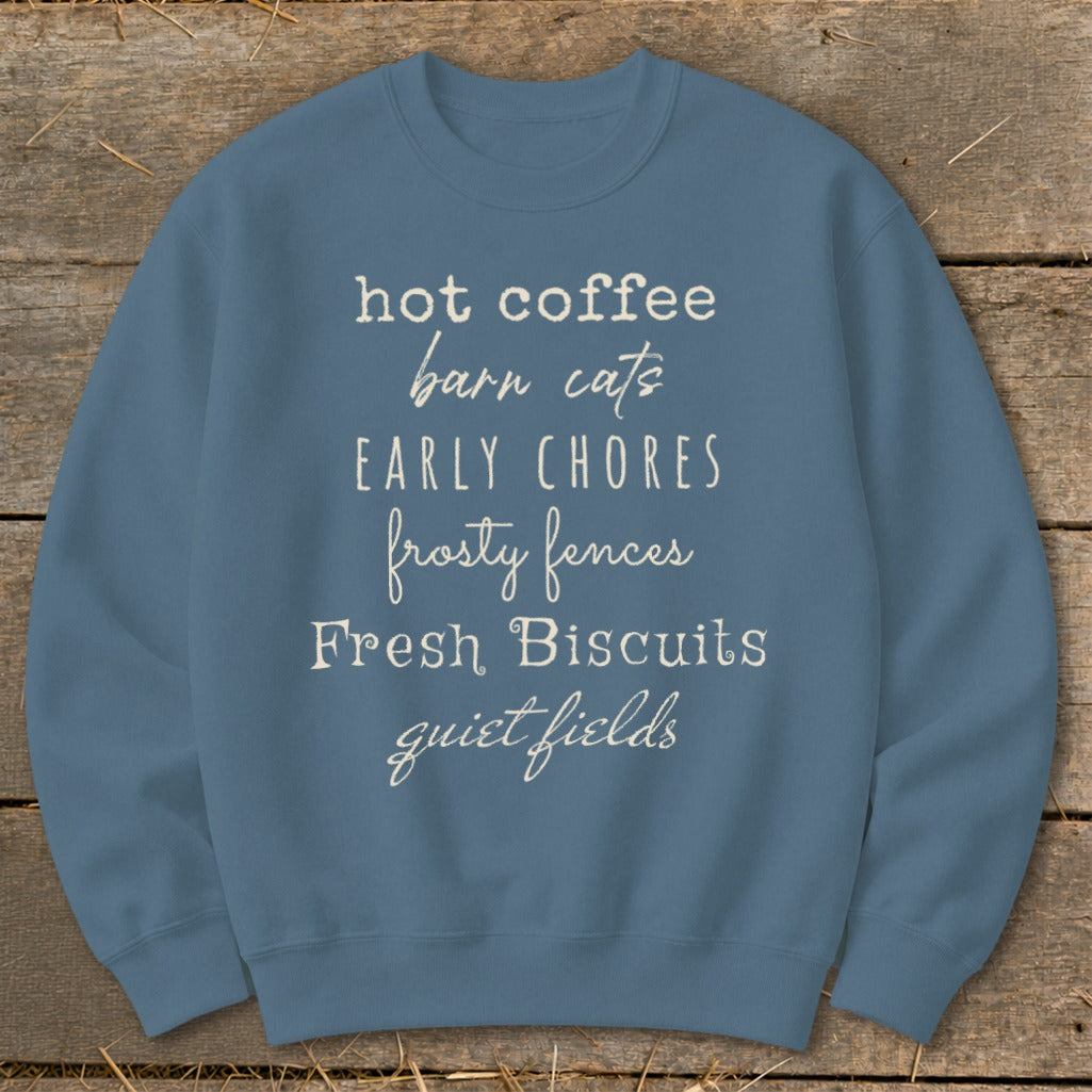 Blue sweatshirt with white text: "hot coffee, barn cats, early chores, frosty fences, Fresh Biscuits, quiet fields."