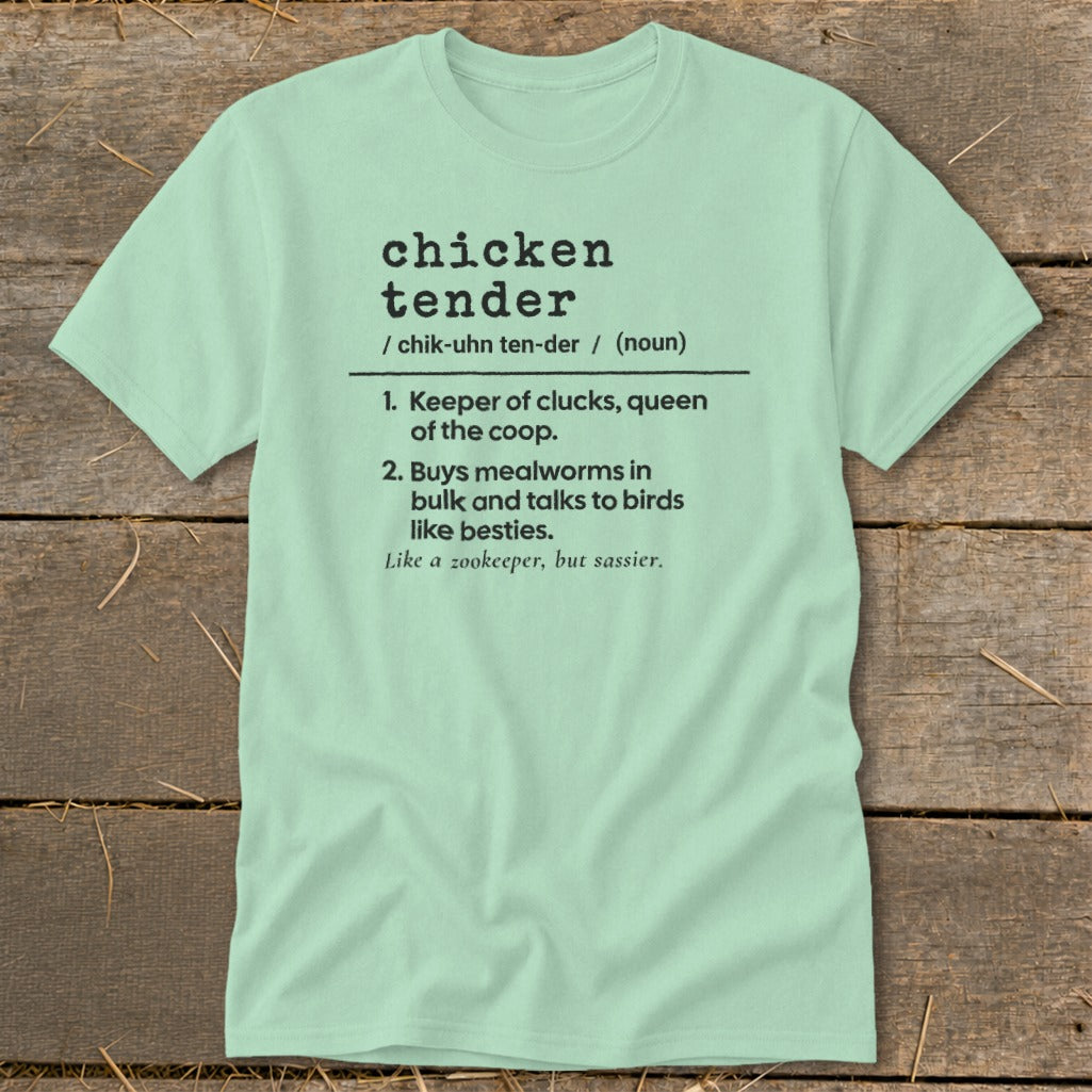 Light green t-shirt with black dictionary-style text defining chicken tender, laid on a wooden background.