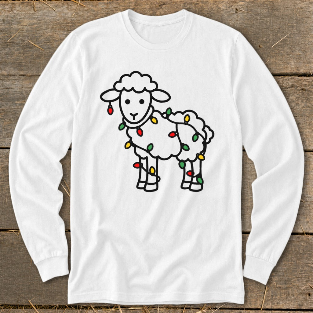A white long-sleeved shirt featuring a cartoon sheep tangled in colorful Christmas lights, displayed on a wooden surface.