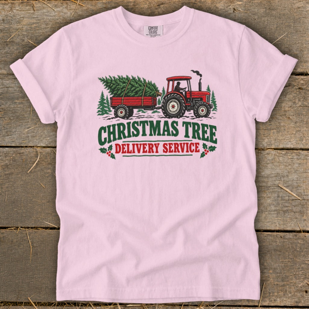 Pink t-shirt with graphic of red tractor pulling Christmas tree delivery trailer.