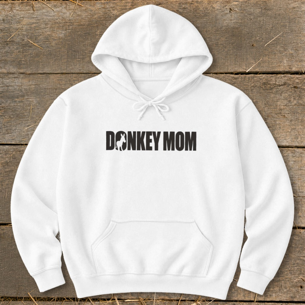 White hooded sweatshirt laid flat on a wooden surface, featuring the black text DONKEY MOM with a silhouette of a donkey replacing the letter O.