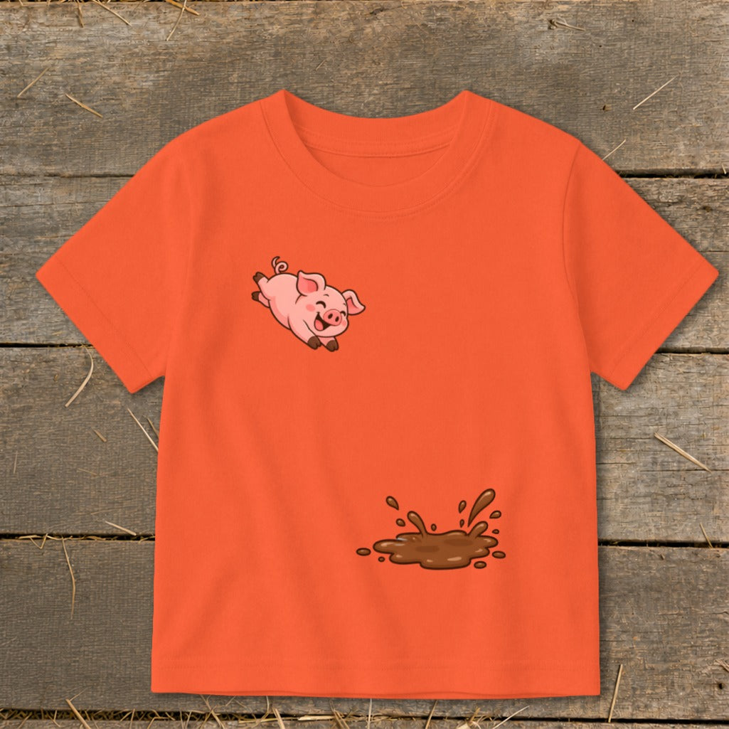 Orange t-shirt with a jumping cartoon pig and a mud splash graphic.