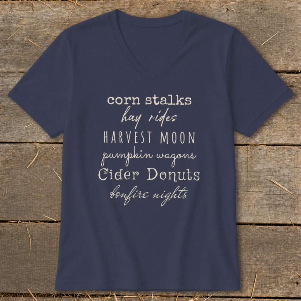 Navy t-shirt with white text listing fall activities: corn stalks, hay rides, harvest moon, pumpkin wagons, cider donuts, bonfire nights.