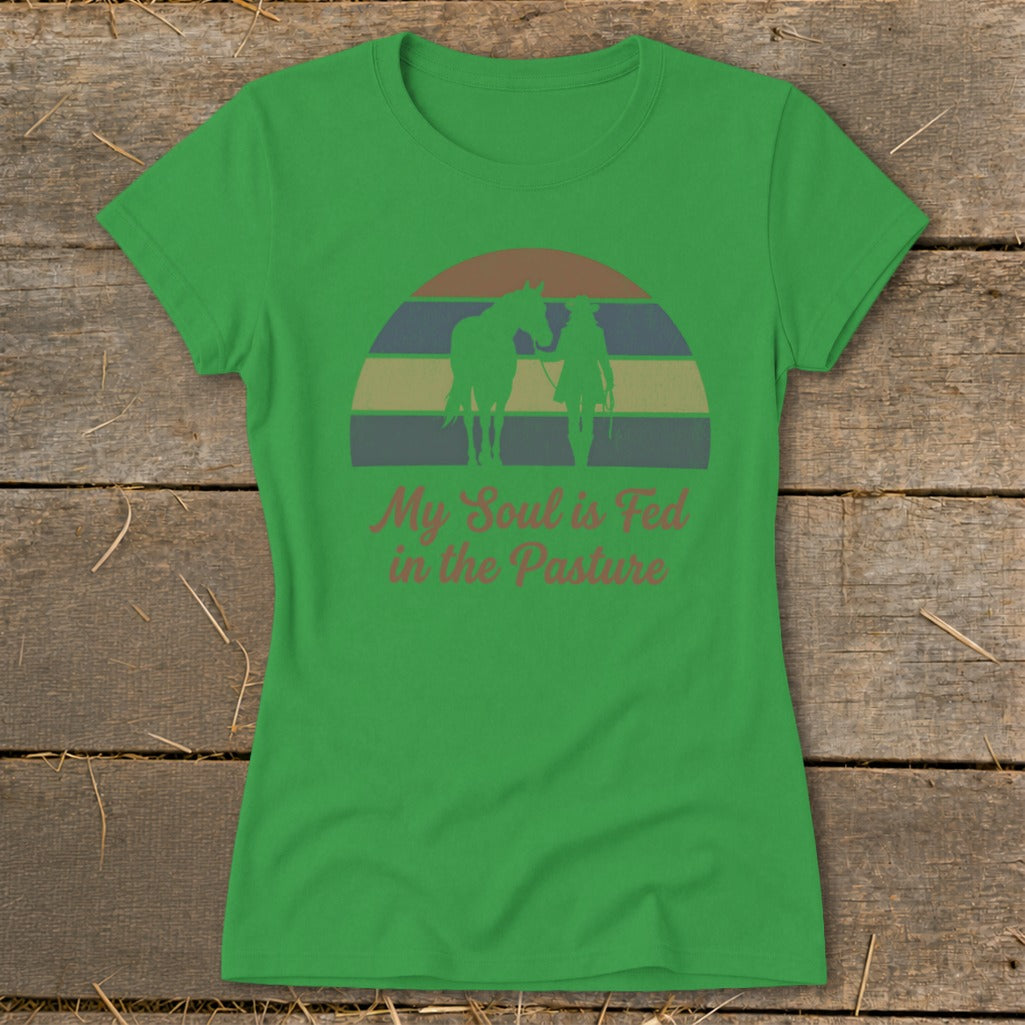 Green t-shirt with silhouette of person and horse, and text "My Soul is Fed in the Pasture".