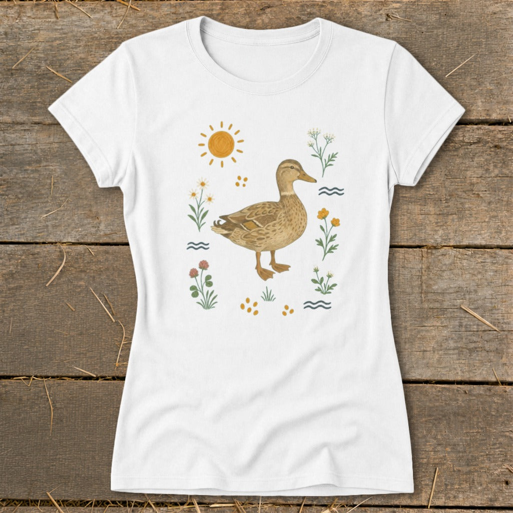 White t-shirt with a brown duck surrounded by wildflowers, sun, and waves.