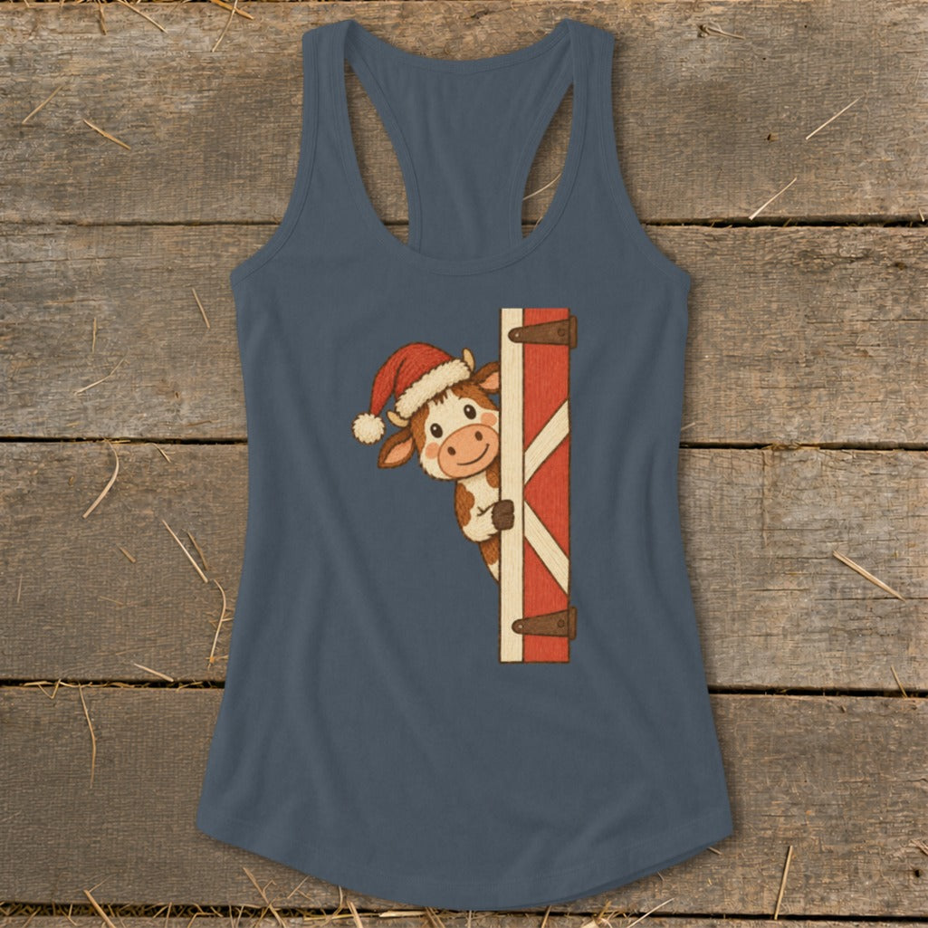 Christmas cow wearing Santa hat peeking around a wooden barn door.