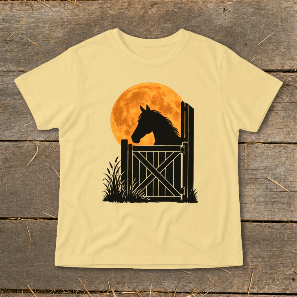 A pale yellow short-sleeved t-shirt featuring a graphic of a horse's silhouette looking over a wooden stable gate against a large orange moon.