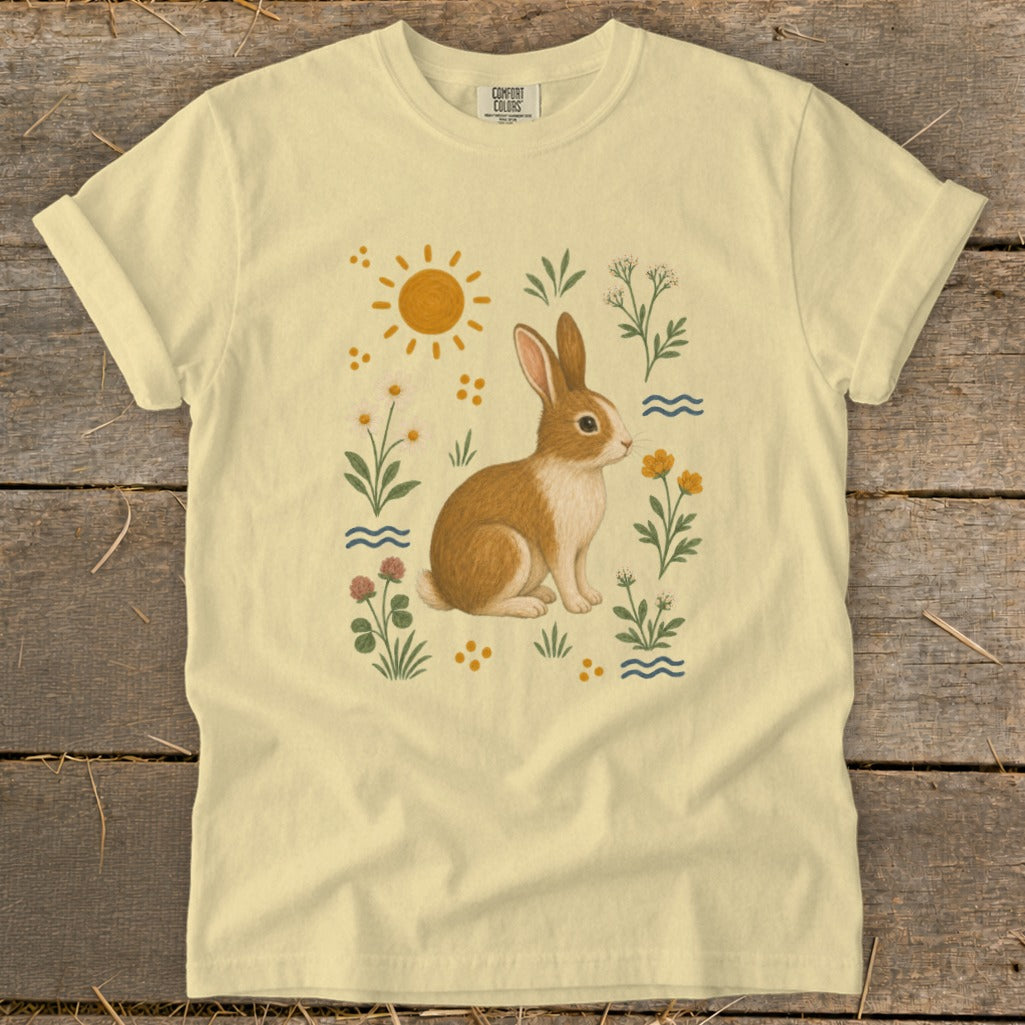 Yellow t-shirt with a brown and white rabbit among flowers and a sun.