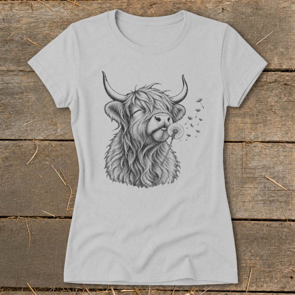 T-shirt graphic of a Highland cow blowing on a dandelion.