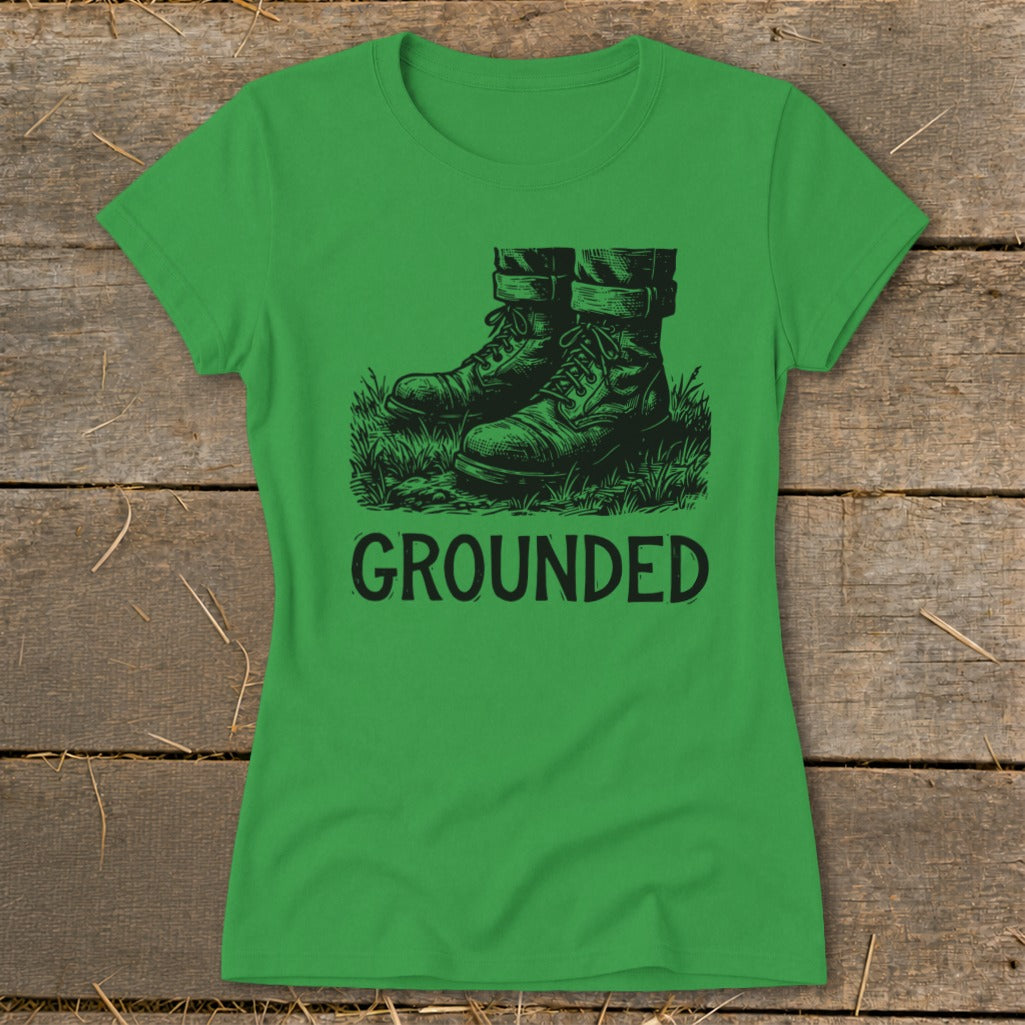 Green t-shirt with black graphic of boots in grass and the word GROUNDED.