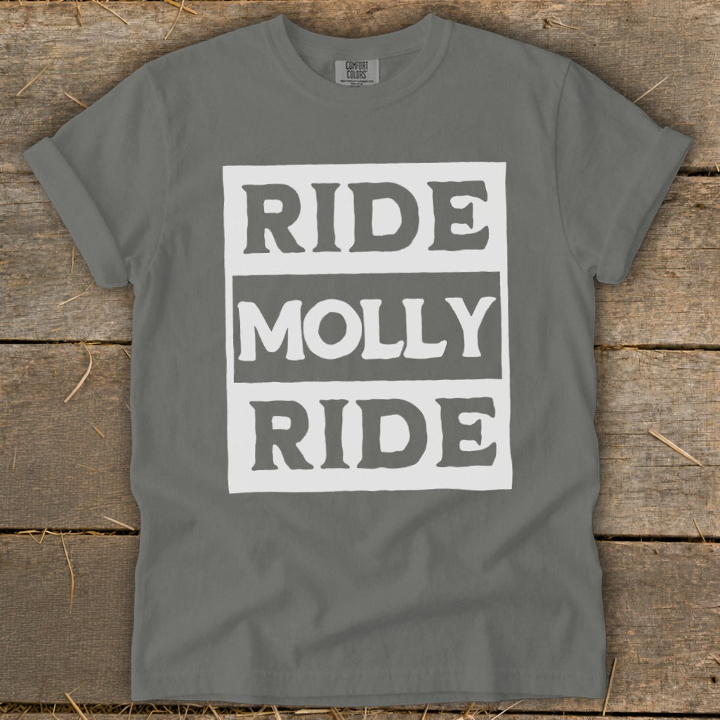 A gray t-shirt with a white block graphic reading RIDE MOLLY RIDE laid flat on wood.