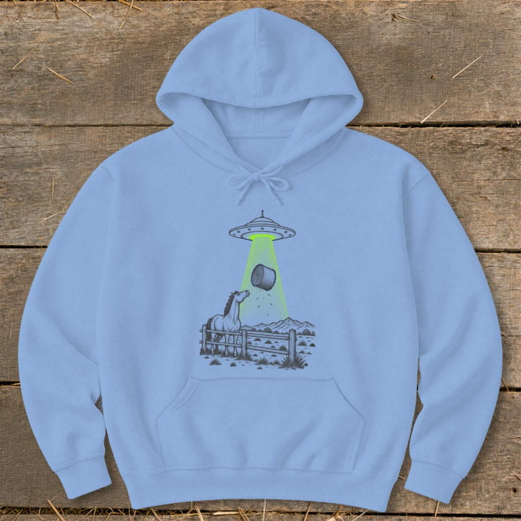Light blue hoodie with a graphic of a UFO abducting a hay bale from a horse enclosure.