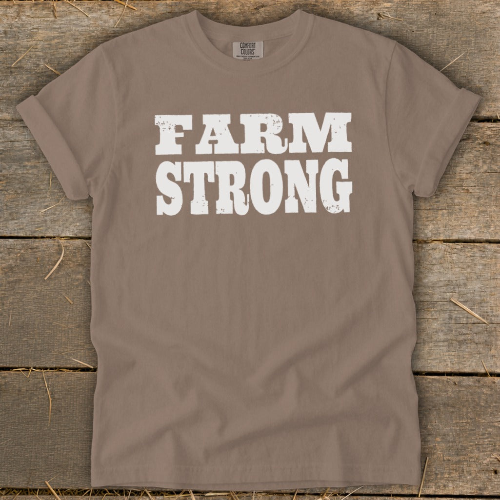 A taupe short-sleeved crewneck t-shirt with the words "FARM STRONG" printed in distressed white text on the chest.