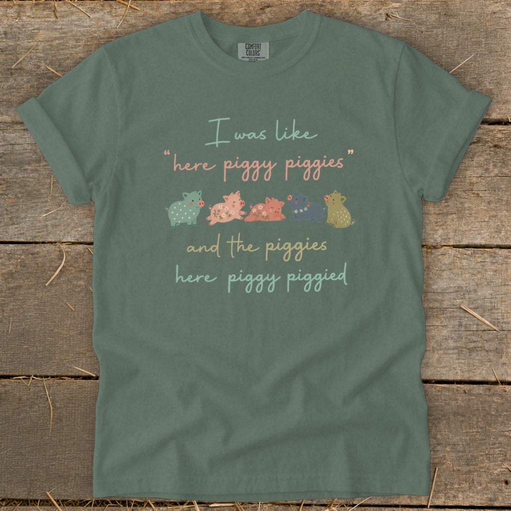 Green t-shirt with "I was like 'here piggy piggies' and the piggies here piggy piggied" and illustration.